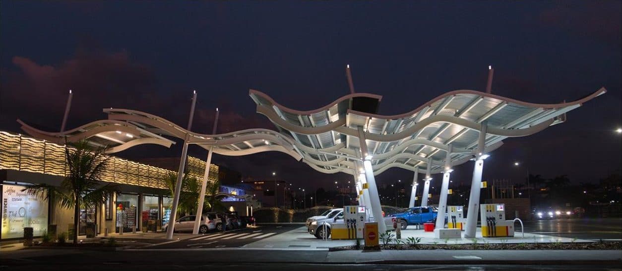 Wave-shaped metal canopy lit above the Victoire station, dusk sky